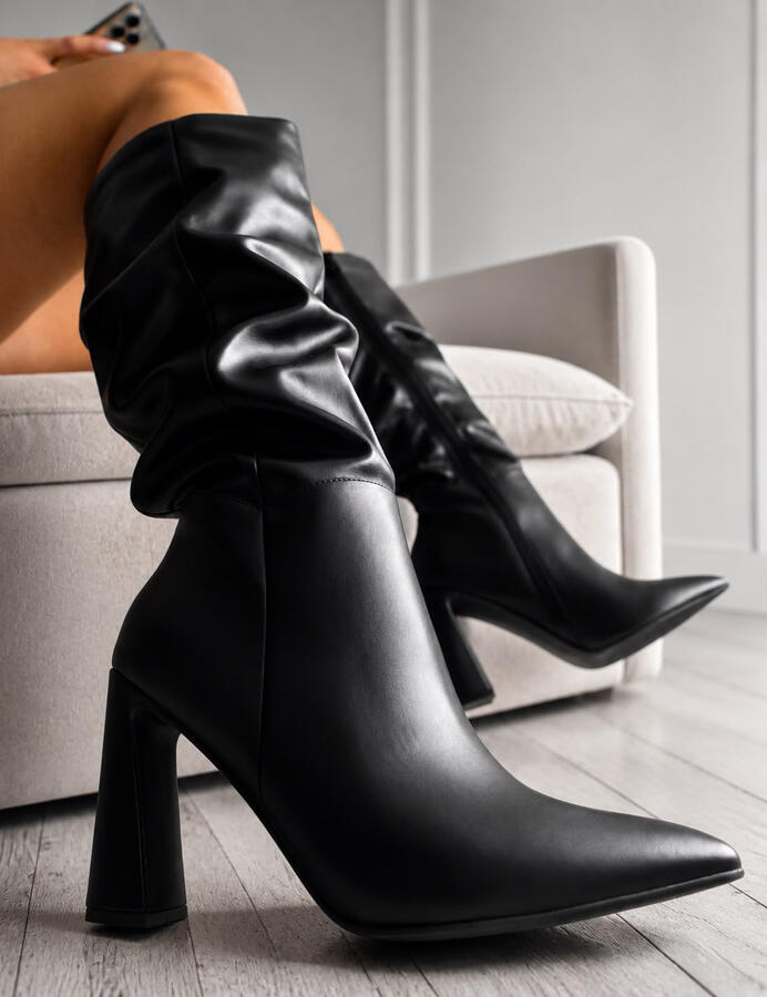 Bota negra arrugada de caña alta con punta fina y taco ancho. Elegante, moderna y perfecta para looks urbanos o de noche. Color: Negro Tallas: Consultar